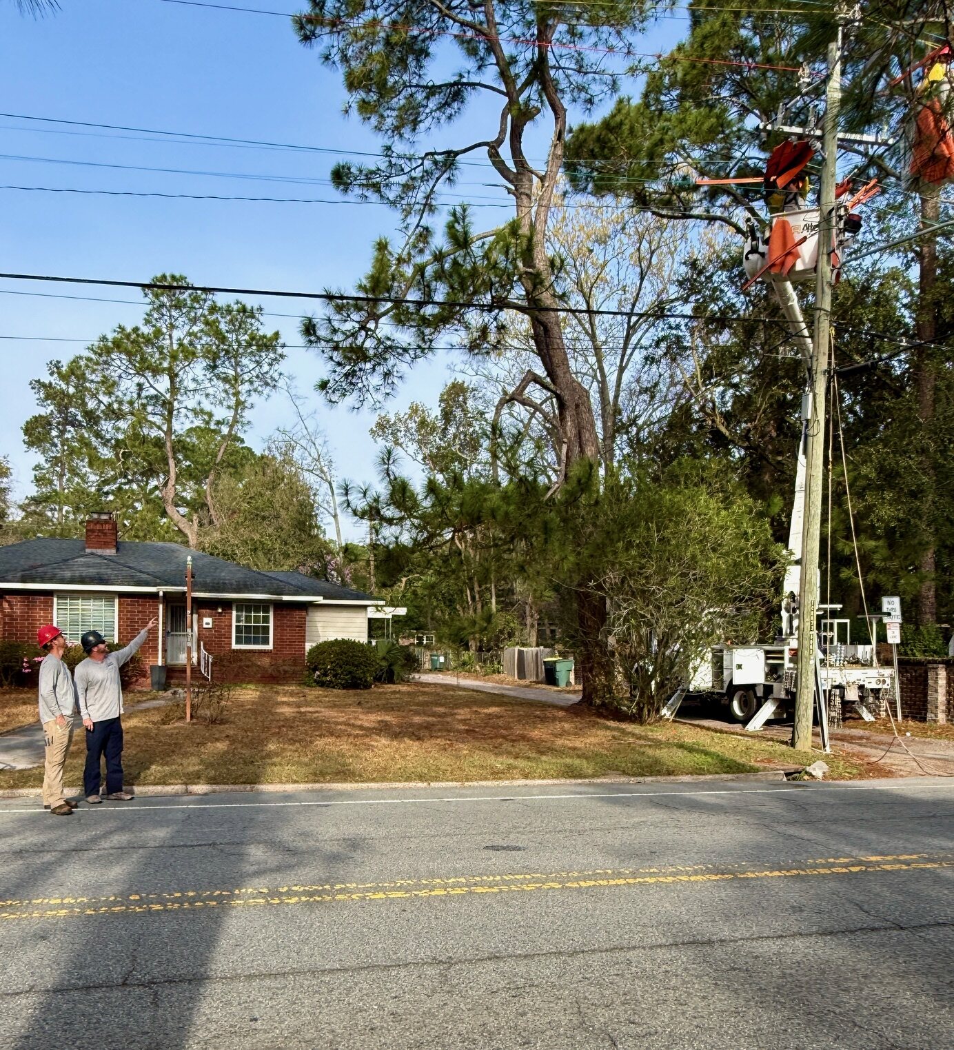 Overhead utility crew and bucket truck working beside a residential street