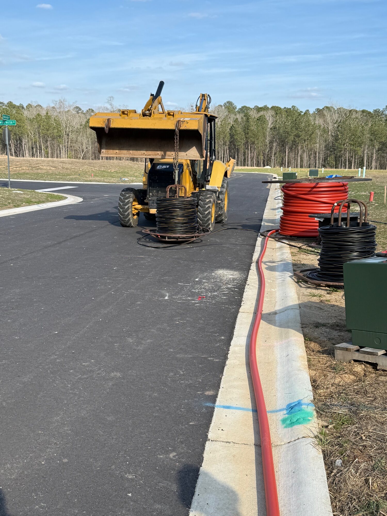 Excavator and conduit materials staged for underground utility construction