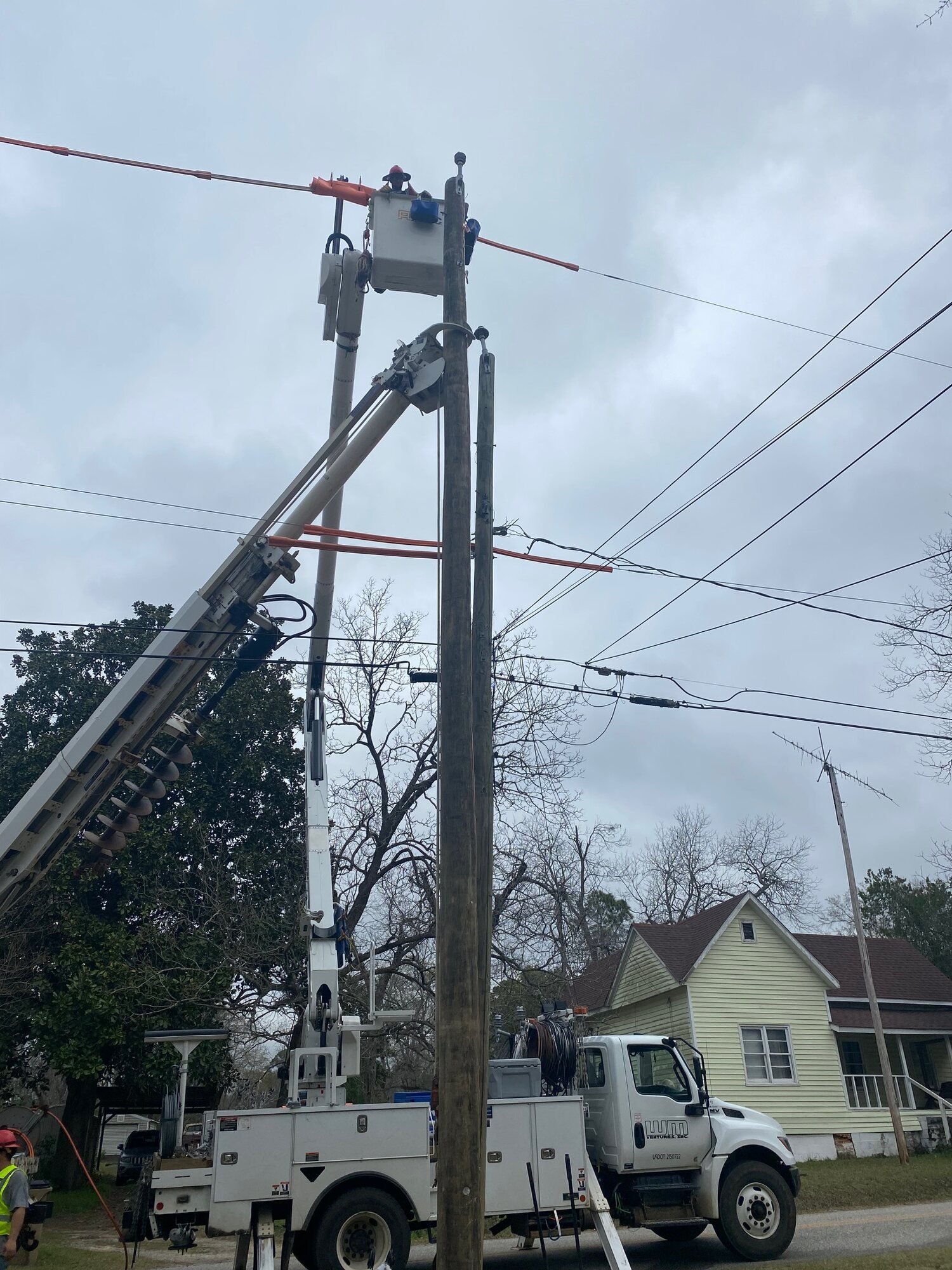 Utility bucket truck raised beside a residential power pole